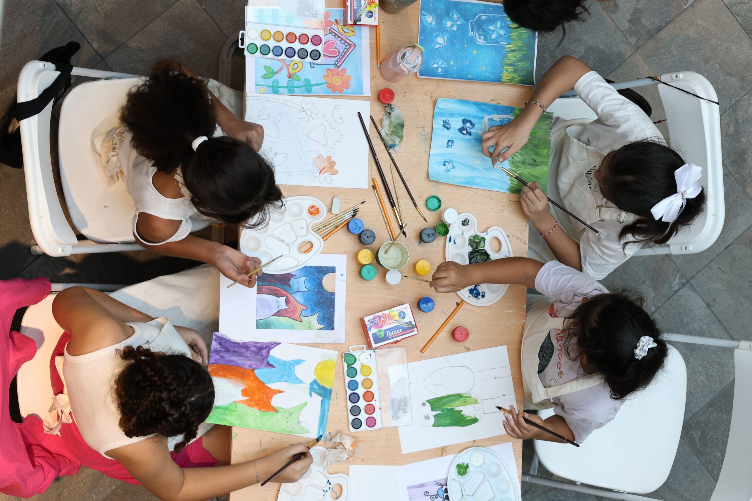 Children paint and draw in an art workshop, utilizing various colors and materials.